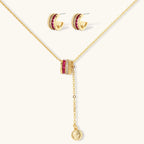 Three-piece jewelry set featuring 14K gold plated pieces with deep red cubic zirconia stones and clear crystals on cream background.