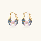 Gold hoop earrings with gradient blue-to-pink enamel in ribbed fan design on beige background