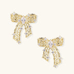 Gold-plated bow earrings with openwork design, marquise center stones, and flowing ribbon tails adorned with zirconia crystals.