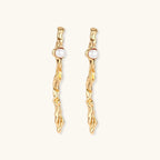 Organic twisted gold-toned drop earrings with white ABS pearls positioned near the top on cream background.