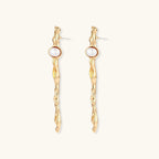 Organic twisted gold-toned drop earrings with white ABS pearls positioned near the top on cream background.